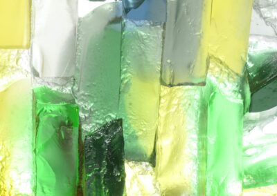 Handmade glass sculpture in blues, yellows and greens and formed as a harbour wall