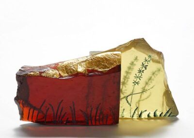 Glass sculpture of a rocky wall engraved with meadow grasses
