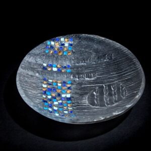 Clear glass bowl with squares of blue and gold against a black backdrop
