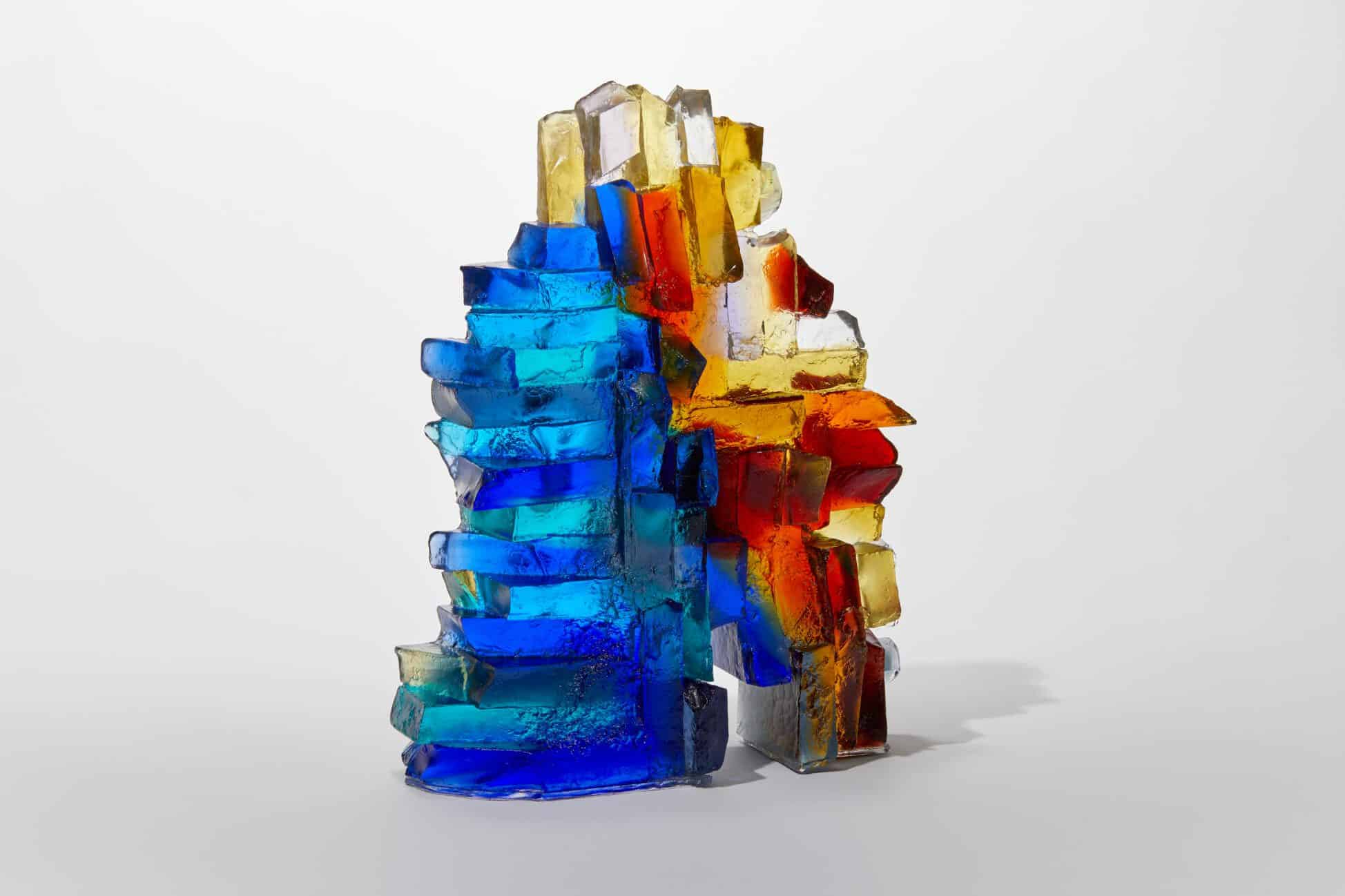 Vibrant glass sculpture with blue, red, and amber colours, showcasing modern art design.