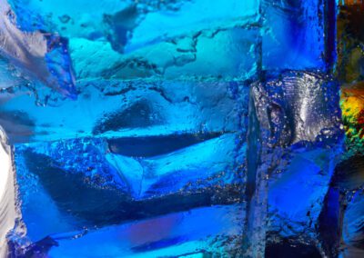 Bright blue glass sculpture with colourful reflections and textures.