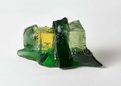 Colourful glass sculpture with green, yellow, and black glass pieces arranged artistically.