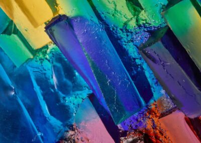 Colourful glass sculpture in various shades of blue, green, yellow, and red, creating an abstract and arti.