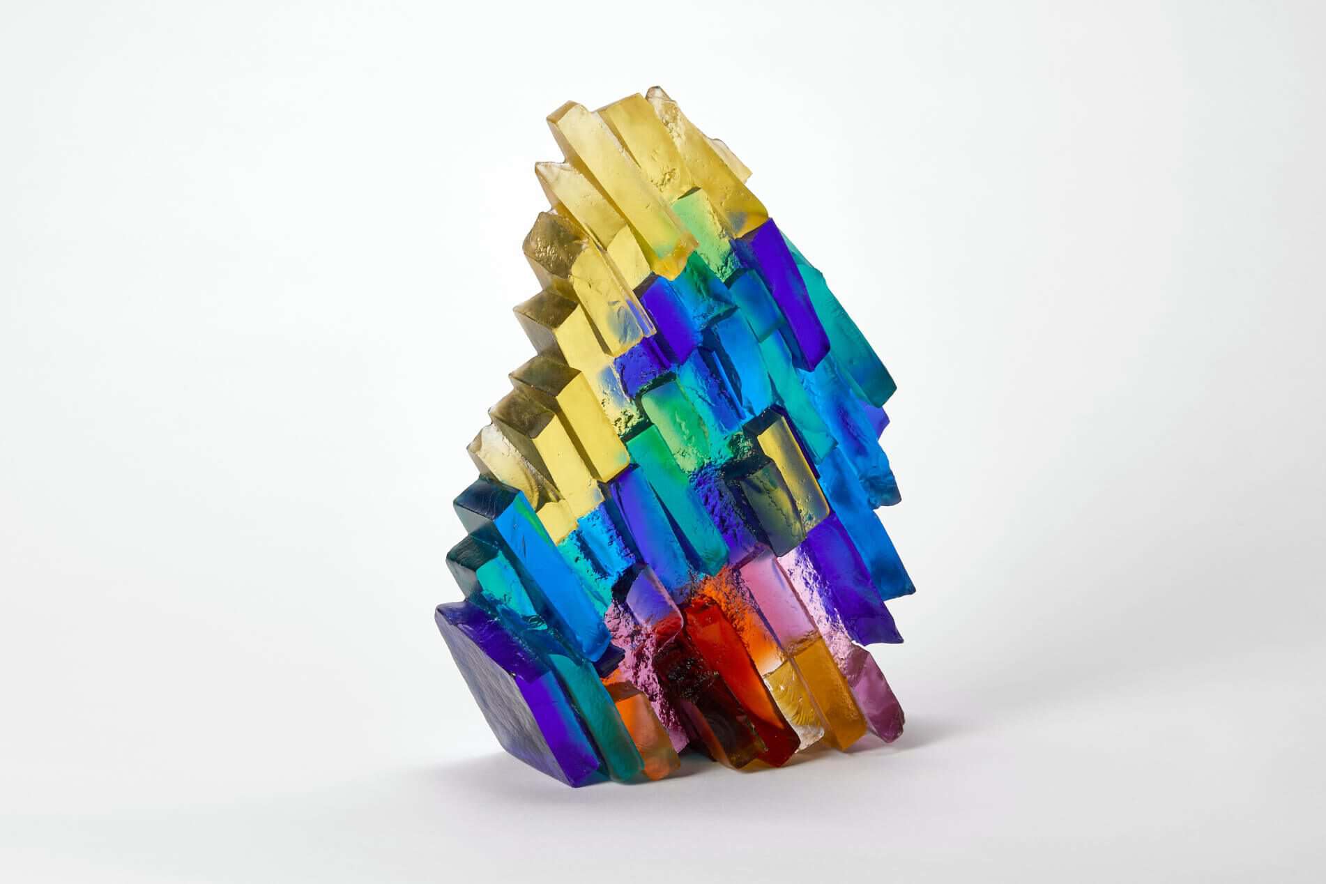 Rainbow coloured glass sculpture with geometric facets and vibrant hues.